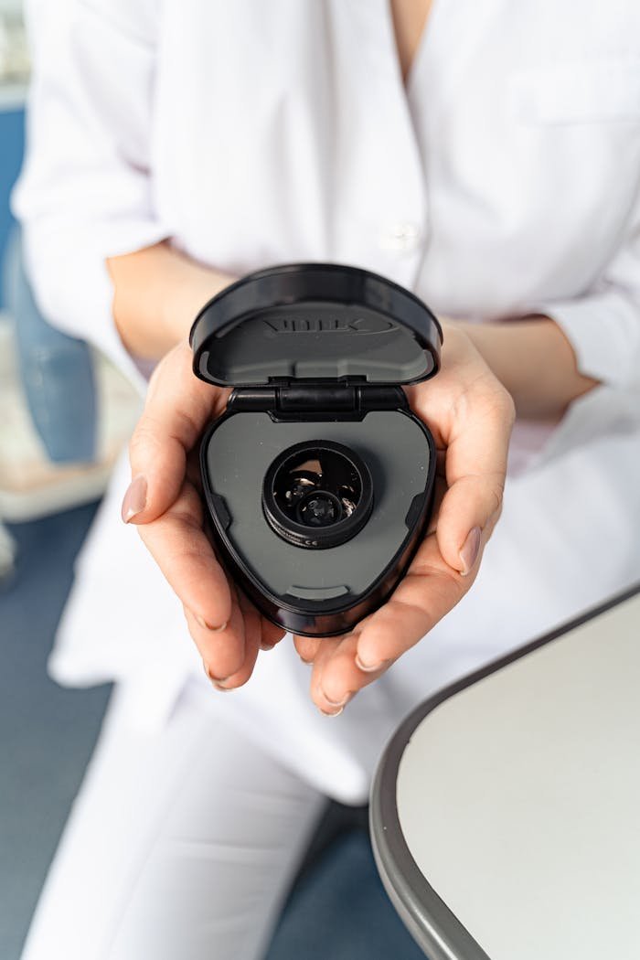 A doctor holding a black optical device in a clinic setting, offering a professional and clean look.